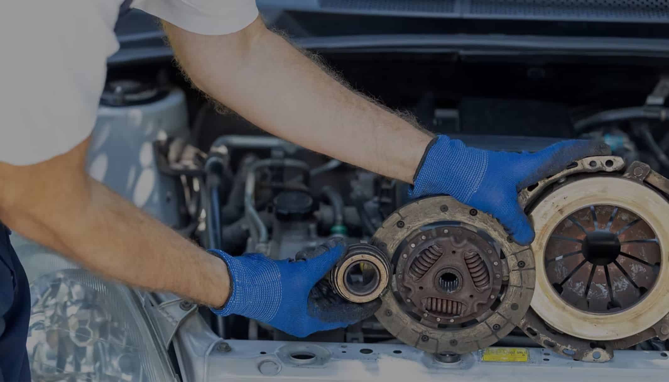Gloved hands fitting a clutch assembly into an engine bay.