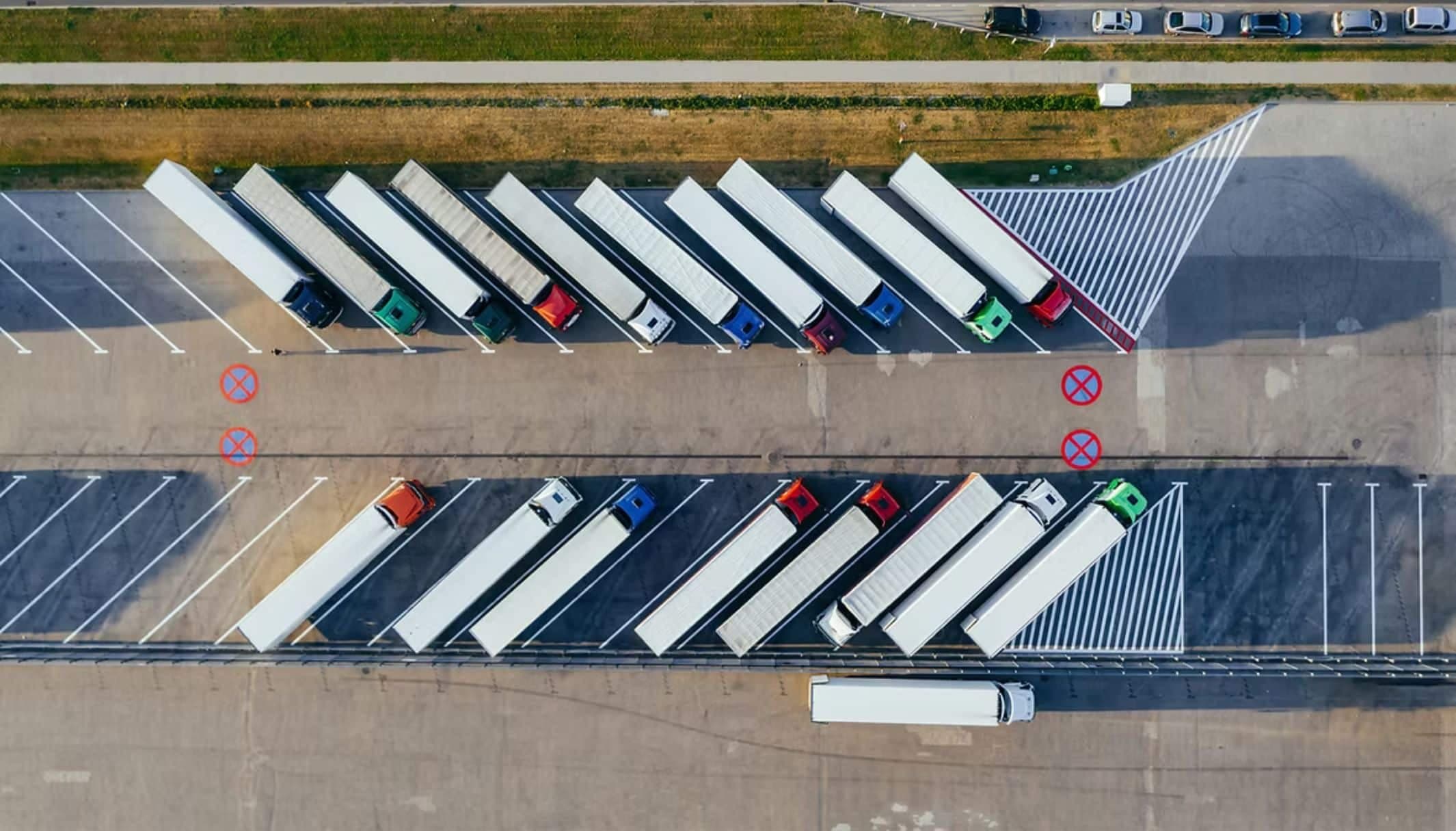 Aerial view of articulated lorries parked in two rows at a distribution yard.