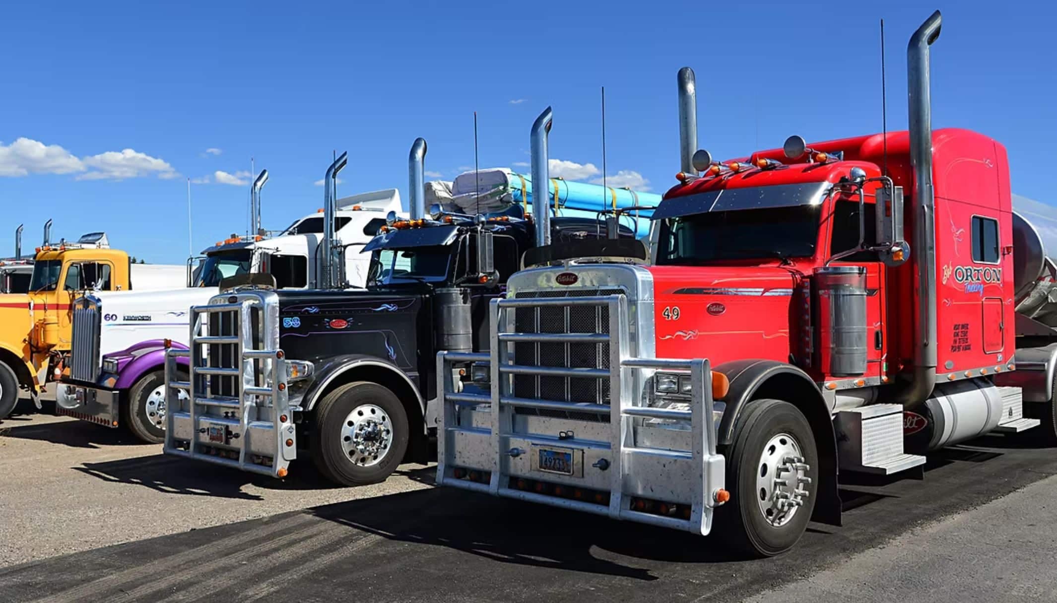 Three long-haul trucks with chrome exhaust stacks parked side by side.