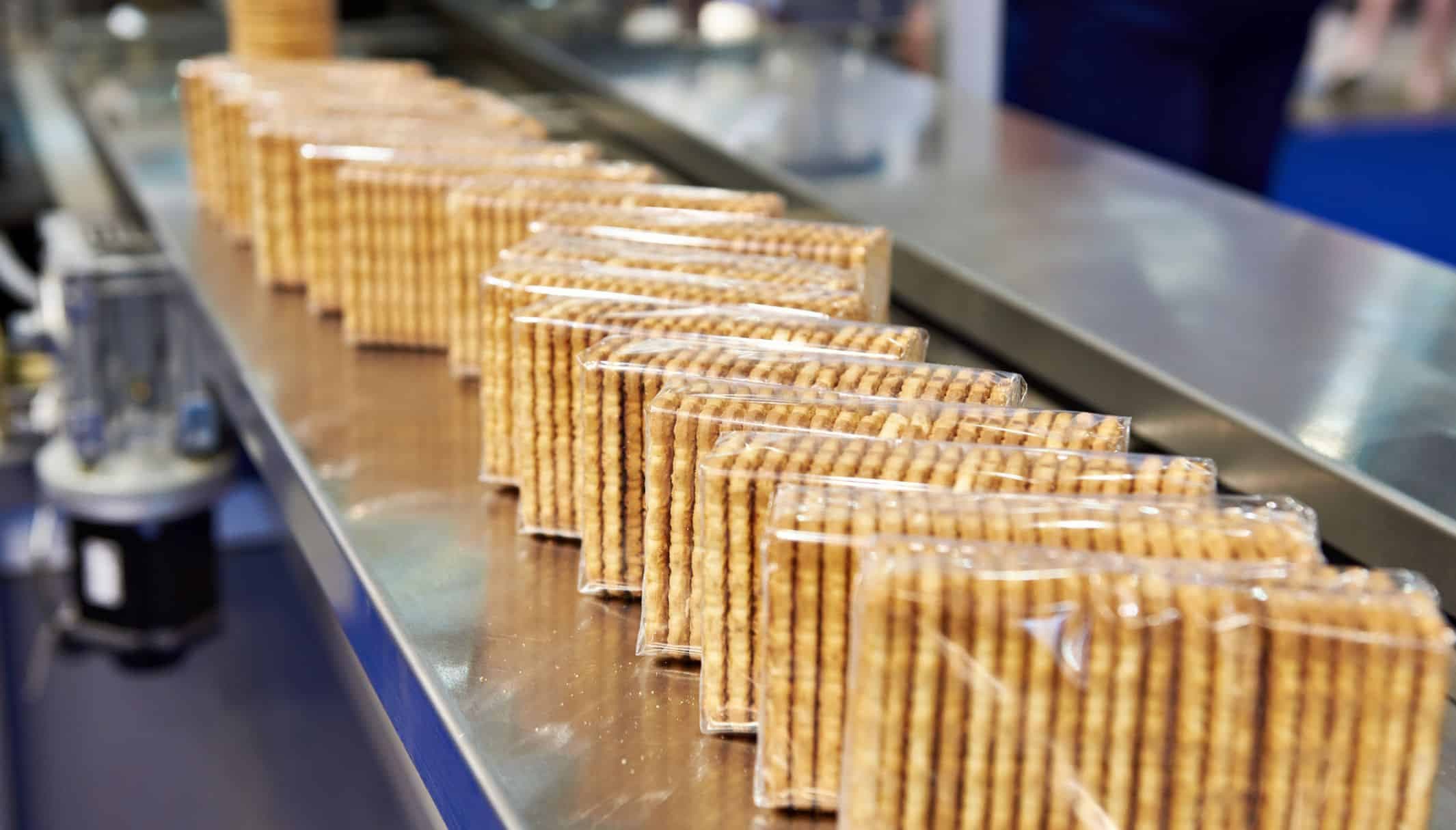 Wrapped wafer packs travelling along a stainless steel conveyor.