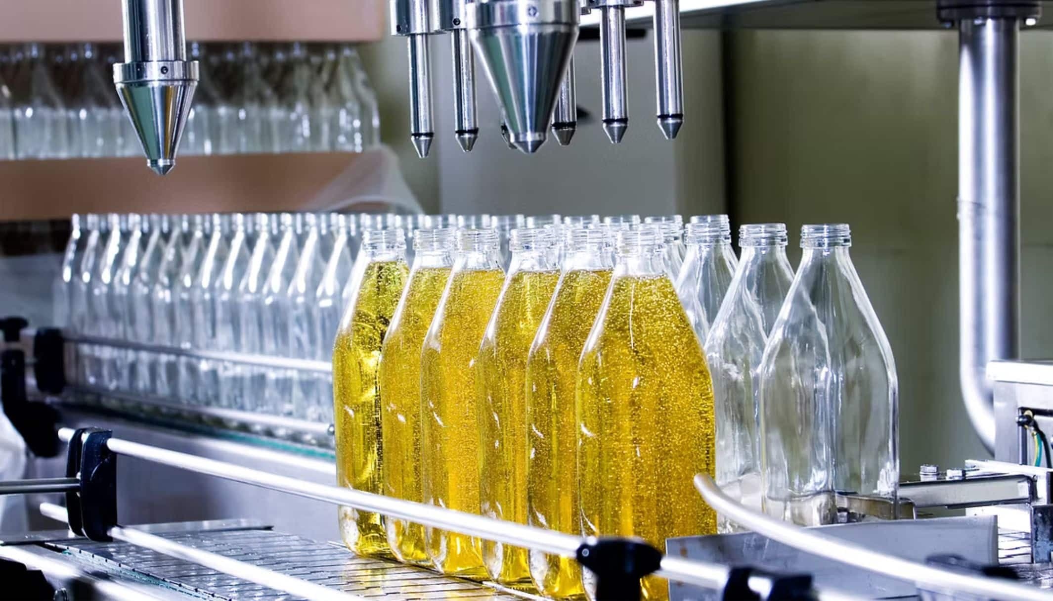 Bottles being filled with yellow liquid on a bottling line.