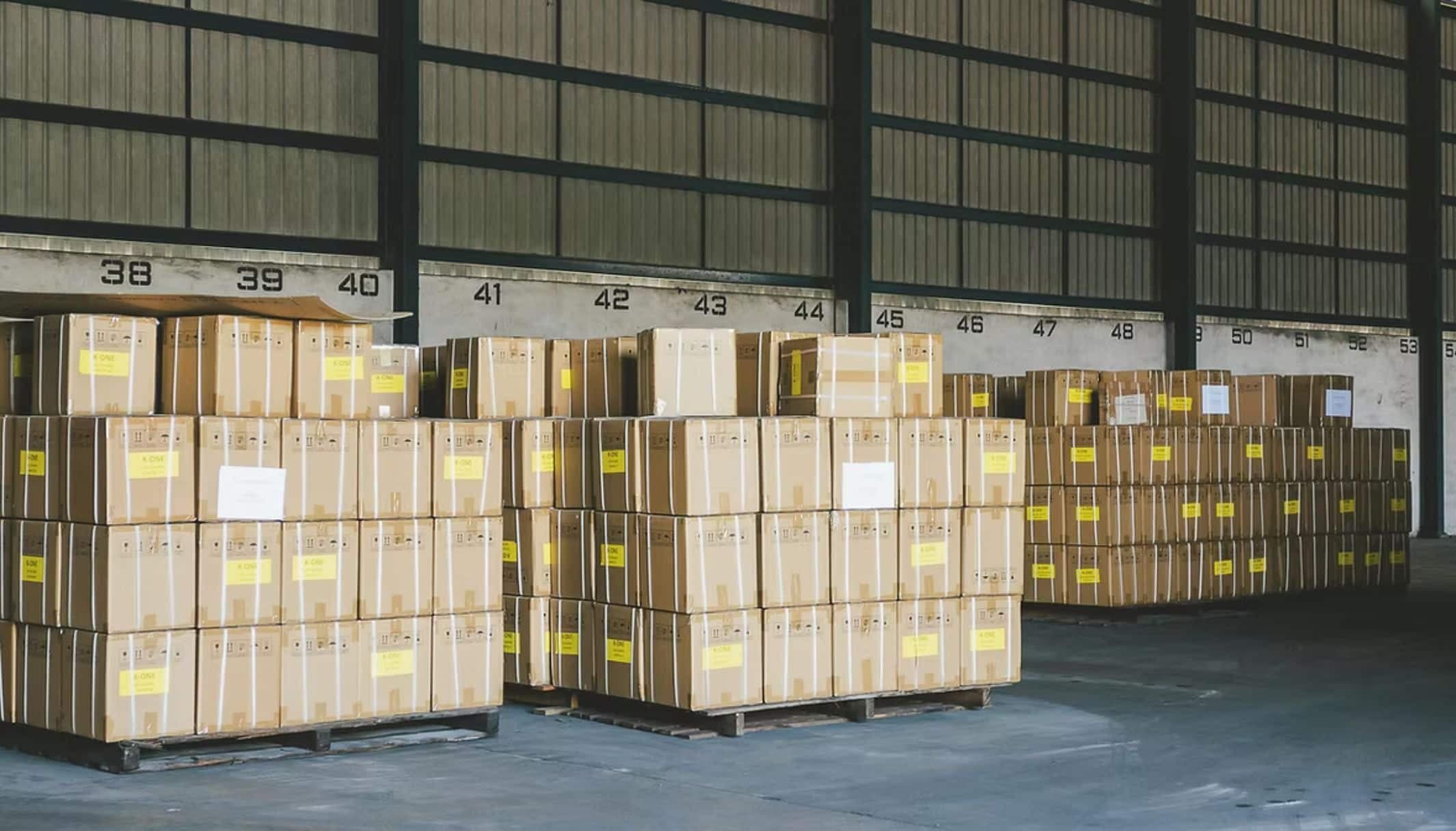 Pallets of boxes stacked in numbered bays inside a warehouse.