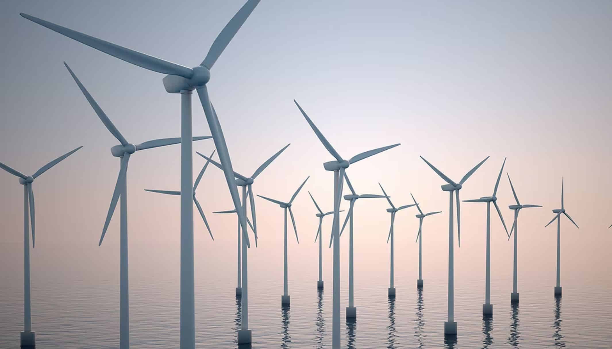 Offshore wind turbines standing in calm water under a pale sky.